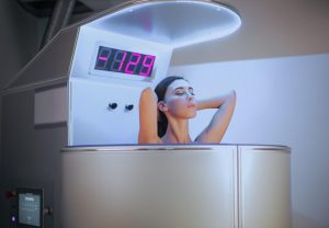 Mujer en cabina de crioterapia durante sesión de recuperación postnatal