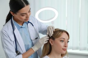Profesional realizando exploración con dermatoscopio en cuero cabelludo de paciente